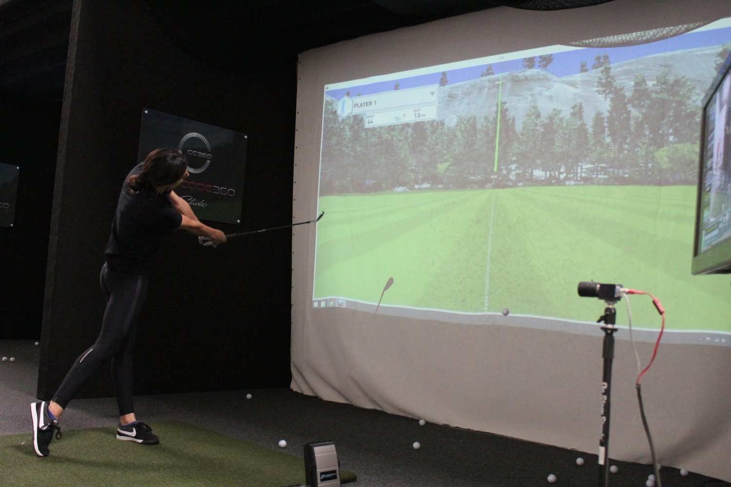 Golfer practicing in a GolfCode 360 Studios indoor simulator bay